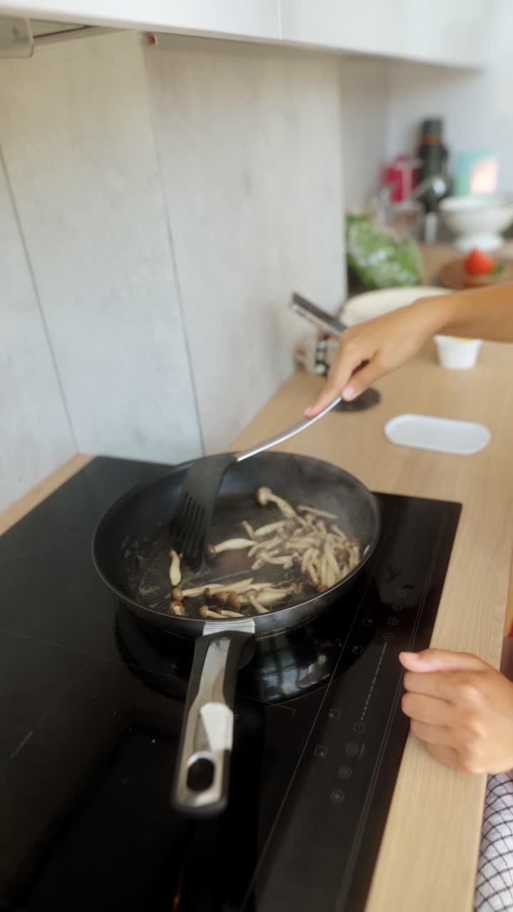 Woman cooking mushrooms in a pan