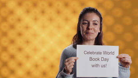 portrait of happy woman holding placard with world book day message