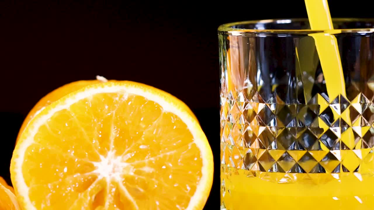 주스가 오렌지 와 함께 유리잔 에 부어지고 있다