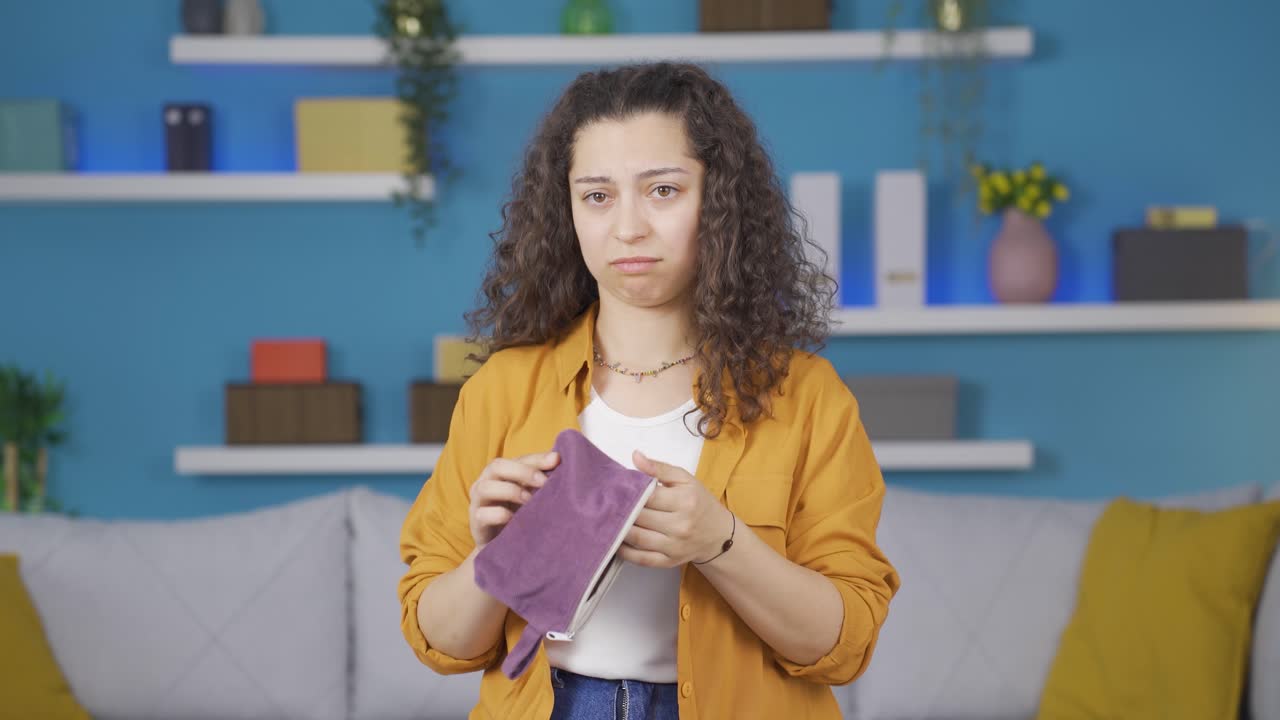 una joven sin dinero mirando su billetera vacía.