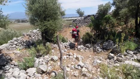 a hiker walking away in the middle of old broken down house ruins in turkey