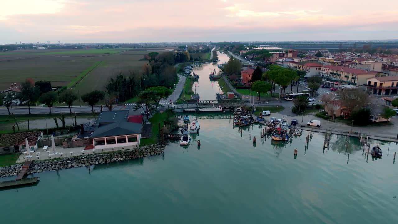 Aerial drone view of Cortellazzo fishing village at sunset near Jesolo, Italy. Scenic estuary where the Piave River meets the Adriatic Sea, featuring the harbor and boats