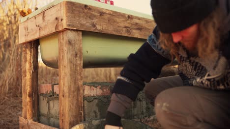el hombre está aplicando cemento para asegurar los ladrillos debajo de la bañera de agua caliente casera - cerca