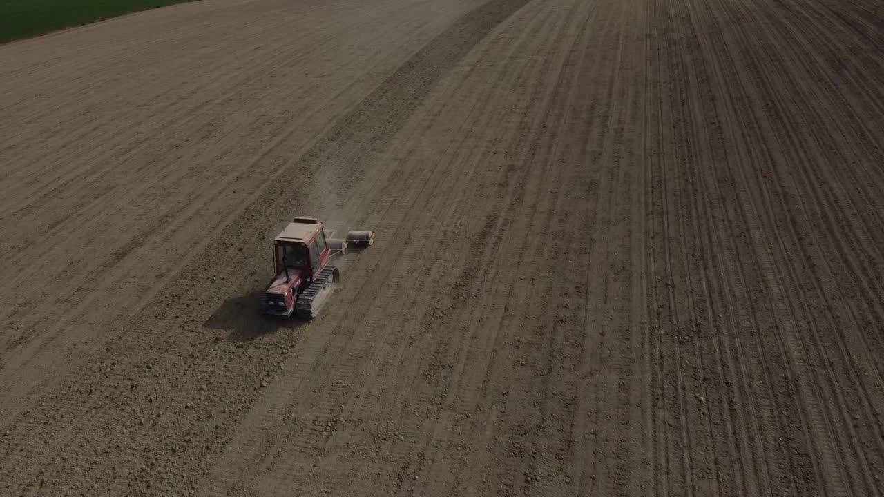 Aerial view of red tractor plowing and preparing the land in scenic agricultural farm