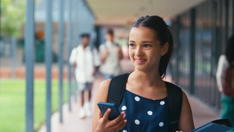 female high school or secondary student looking at social media or internet on phone outdoors