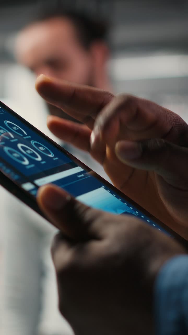 Vertical Video Close up of black employee engages in charts analysis session on tablet