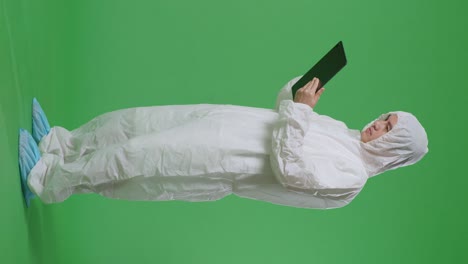 full body side view of asian male scientist using a tablet while standing on green screen background