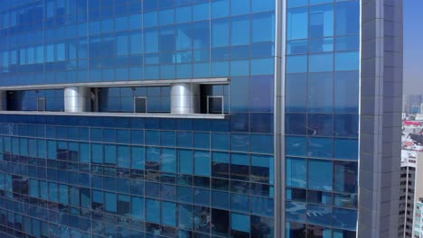 Drone-flying-beside-skyscraper-blue-windows-Mexico-city-day-time