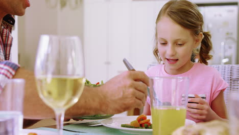 padre sirviendo ensalada a su hija en la mesa del comedor
