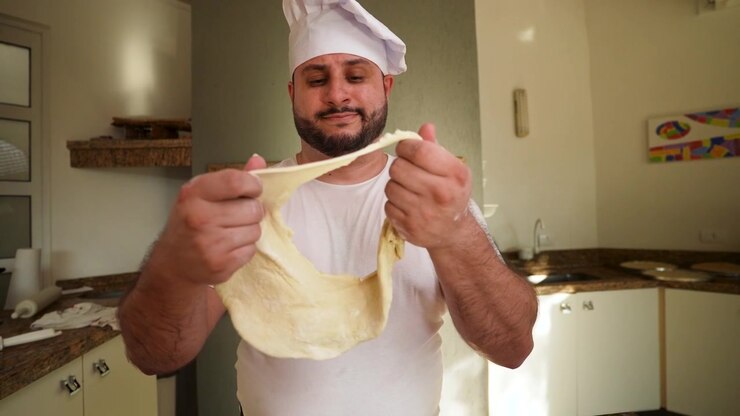 Un primo piano della reazione espressiva di uno chef mentre esamina l'impasto inutilizzabile tra le sue mani