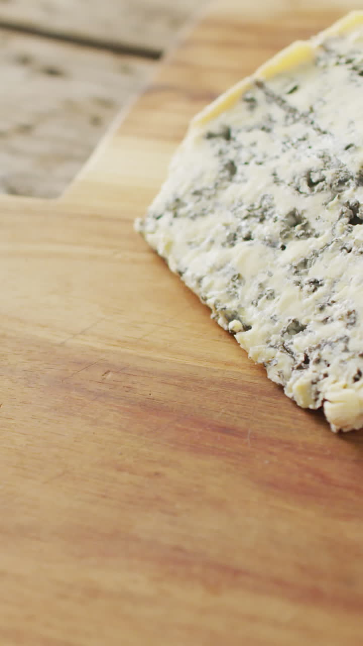 Video di uno spicchio di formaggio erborinato su tagliere, su tavolo di legno rustico