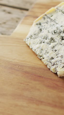 video de una cuña de queso azul en una tabla de cortar, en una mesa de madera rústica