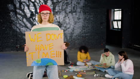 serious young environmental activist holding a cardboard with we don't have time" inscription and looking at the camera"