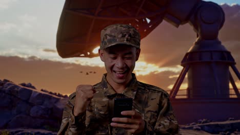 close up of asian man soldier looking at smartphone then screaming goal celebrating while standing with satellite dish