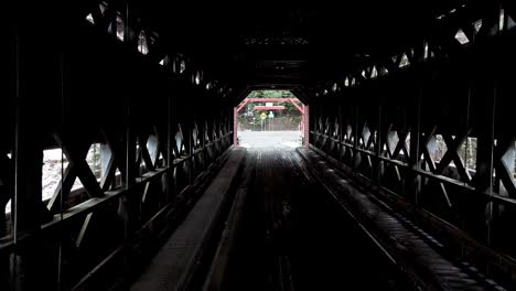 going through a covered bridge with a little bit of snow crossing a river in quebec, canada