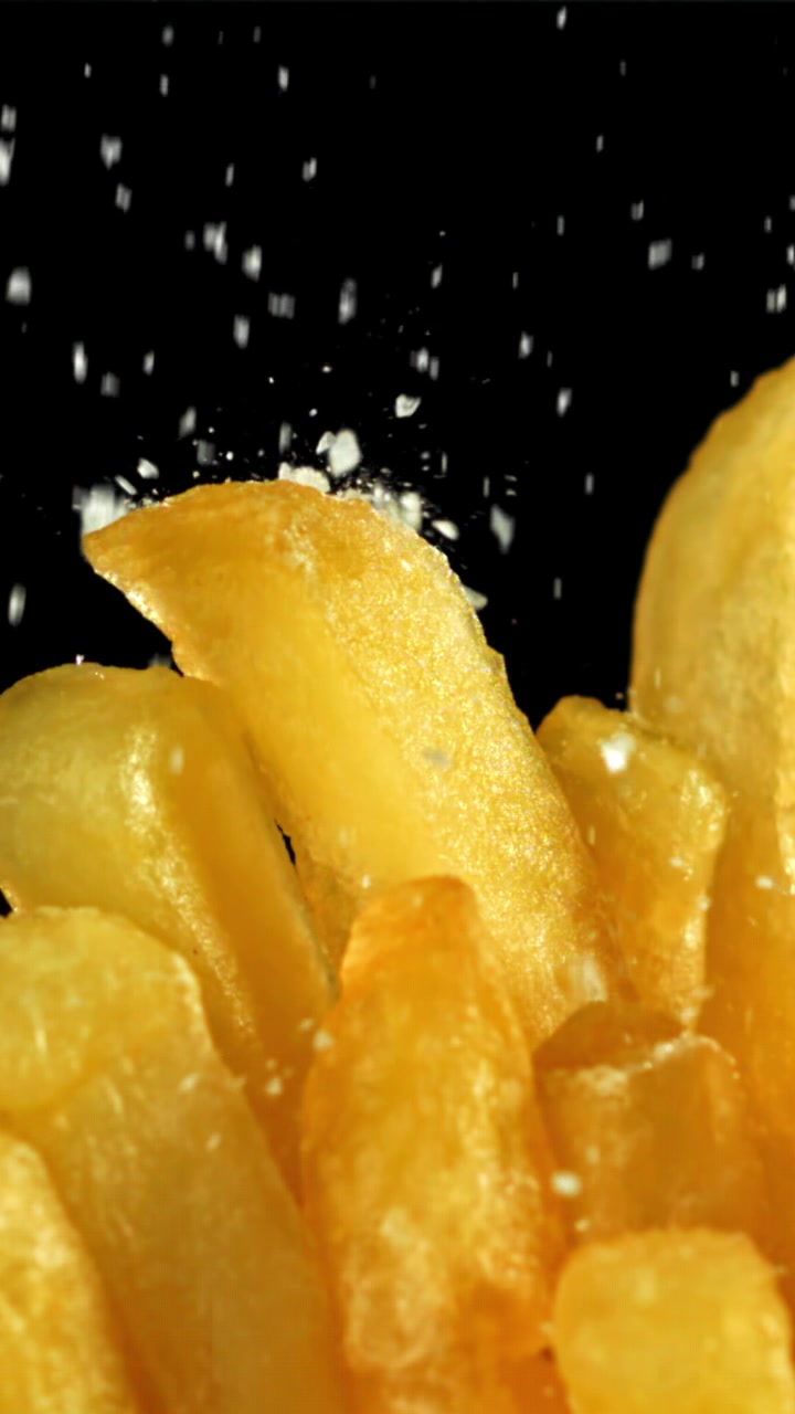 Salt Being Sprinkled on Golden French Fries in Slow Motion