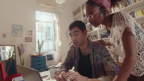 young couple using laptop and having talk in cozy room