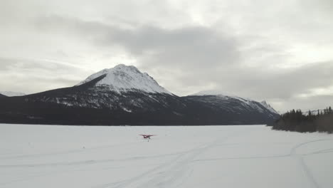 toma aérea de un avión despegando de un lago congelado en invierno