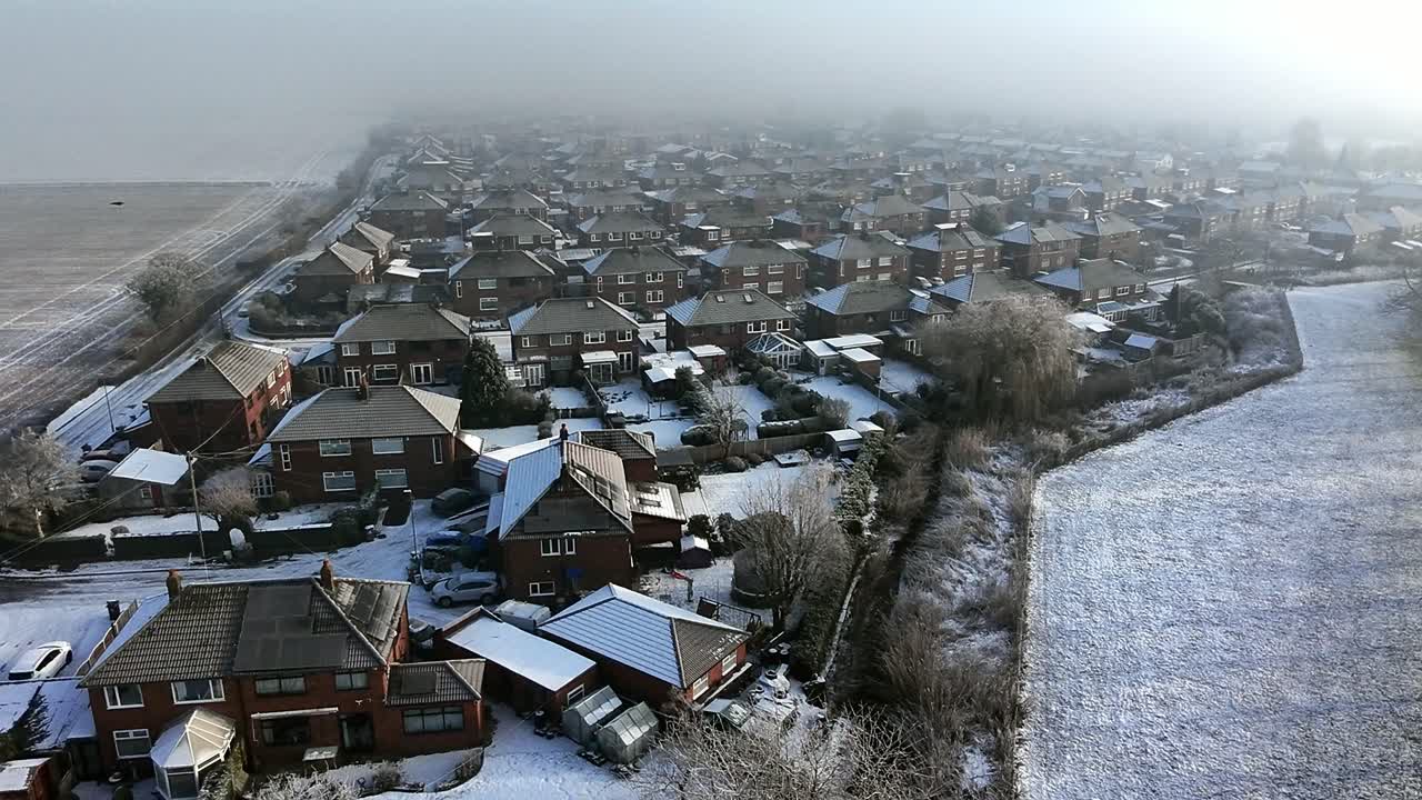 Frosty morning mist aerial view covering British farmland meadow and small town neighbourhood houses