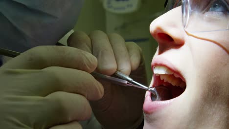 dentista examinando a una paciente femenina con herramientas