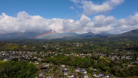 cinematic arial view with rainbow in cloudy sky in kauai, hawaii