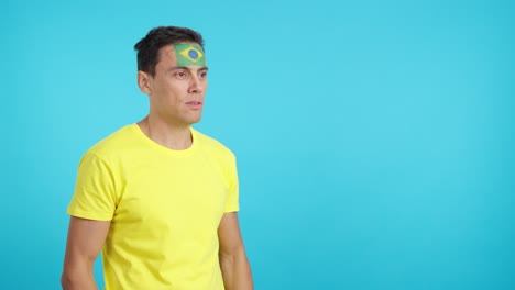 Happy man with brazilian flag painted on face looking away