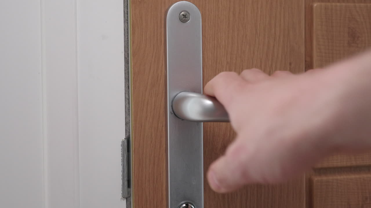 un primer plano de la mano de un hombre cerrando una puerta, centrándose en el mango