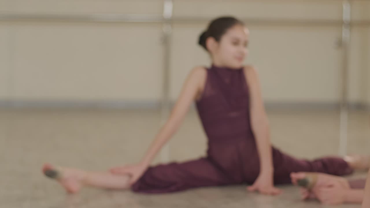 un grupo de jóvenes estudiantes de ballet con ropa de baile negra practicando posiciones en un amplio estudio de ballet con pisos de madera y barras montadas en la pared. expresiones enfocadas y movimientos sincronizados.