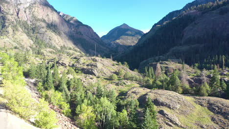 Aerial-Drone-Rising-Motion-of-Cars-Driving-on-Highway-550-Through-Ouray-Colorado-Mountains-to-Hiking-Trails-Surrounded-by-Thick-Pine-Tree-Forest-and-Power-Lines