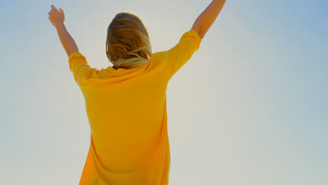 rear view of young caucasian woman standing with arms outstretched on the beach 4k