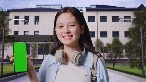 smiling teenager with green screen phone on campus