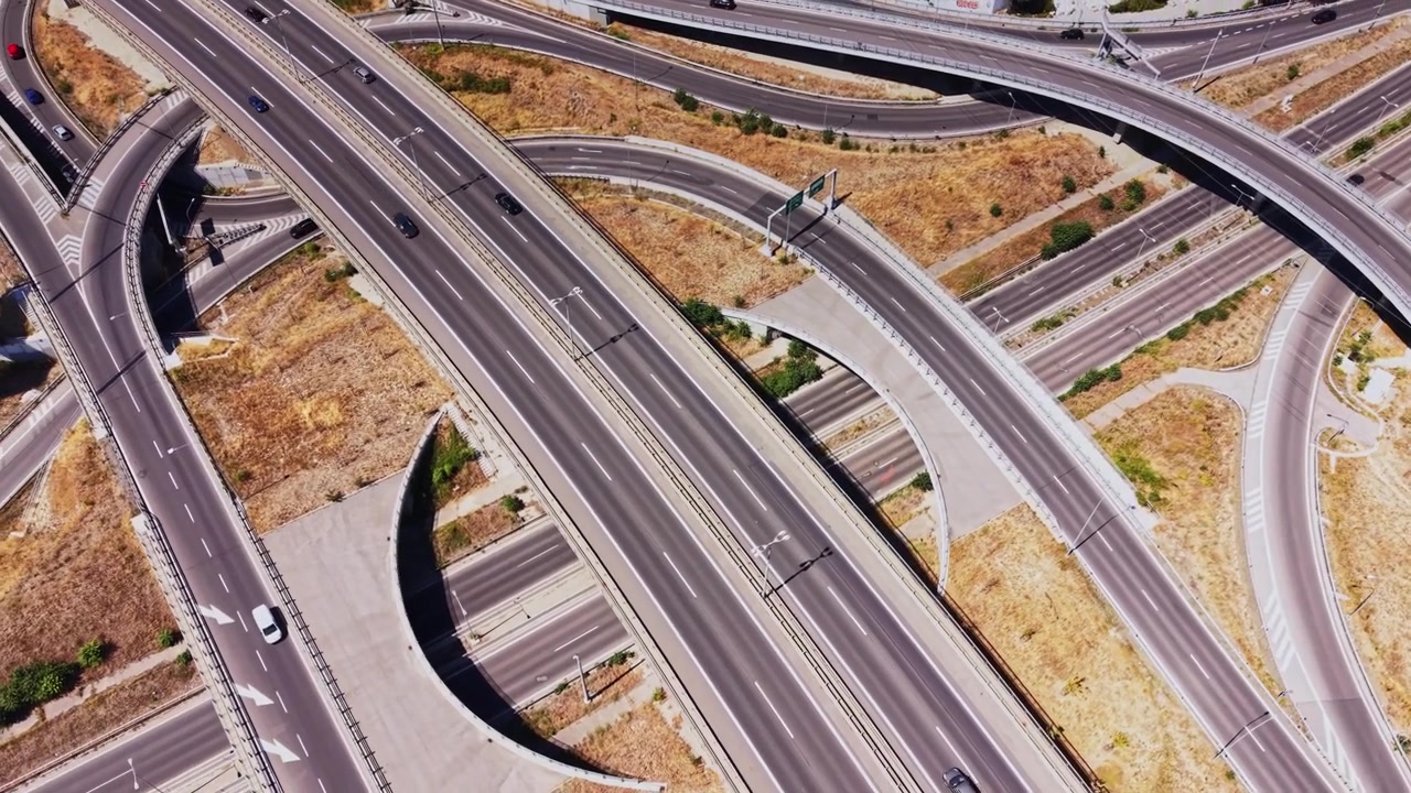 Traffic flows on a roundabout near a highway in a sunny area