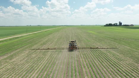 aerial, tractor spraying pesticides on crops in rural agricultural farm field