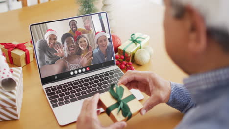 senior biracial man having christmas video call with diverse people