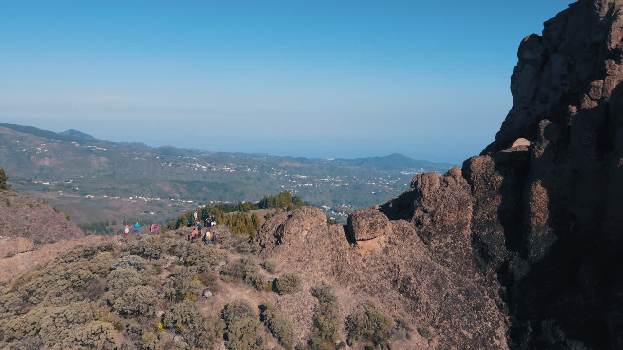 toma aérea cinematográfica que revela el roque saucillo y donde hay un grupo de turistas bajando la montaña