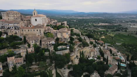 Toma-Aérea-Hacia-Atrás-Del-Histórico-Pueblo-Francés-De-Gordes-En-La-Colina-Durante-El-Día-Soleado-En-Francia