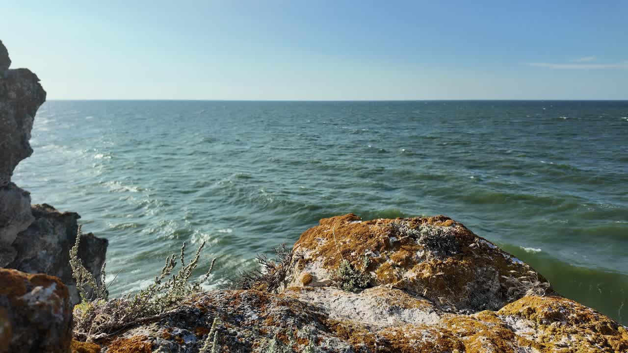 Waves gently crash against the rocky shoreline as the sun sets, illuminating the beautiful coastline of Crimea by the Sea of Azov