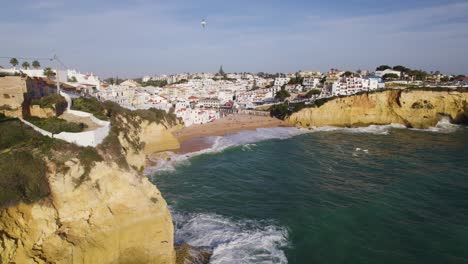 aerial flying past alto da praia do carvoeiro with beach in background and waves breaking