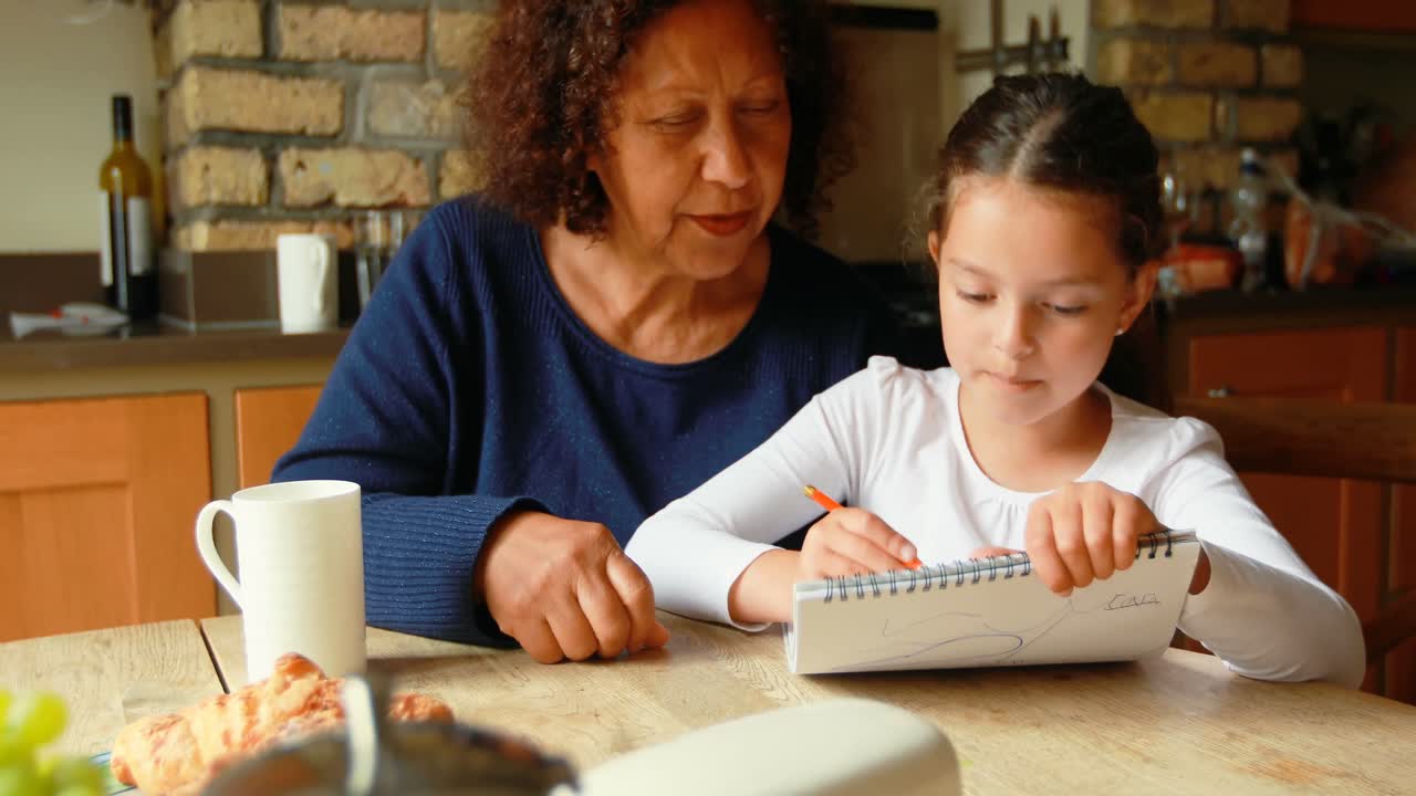 abuela ayudando a su nieta en los estudios en la cocina 4k