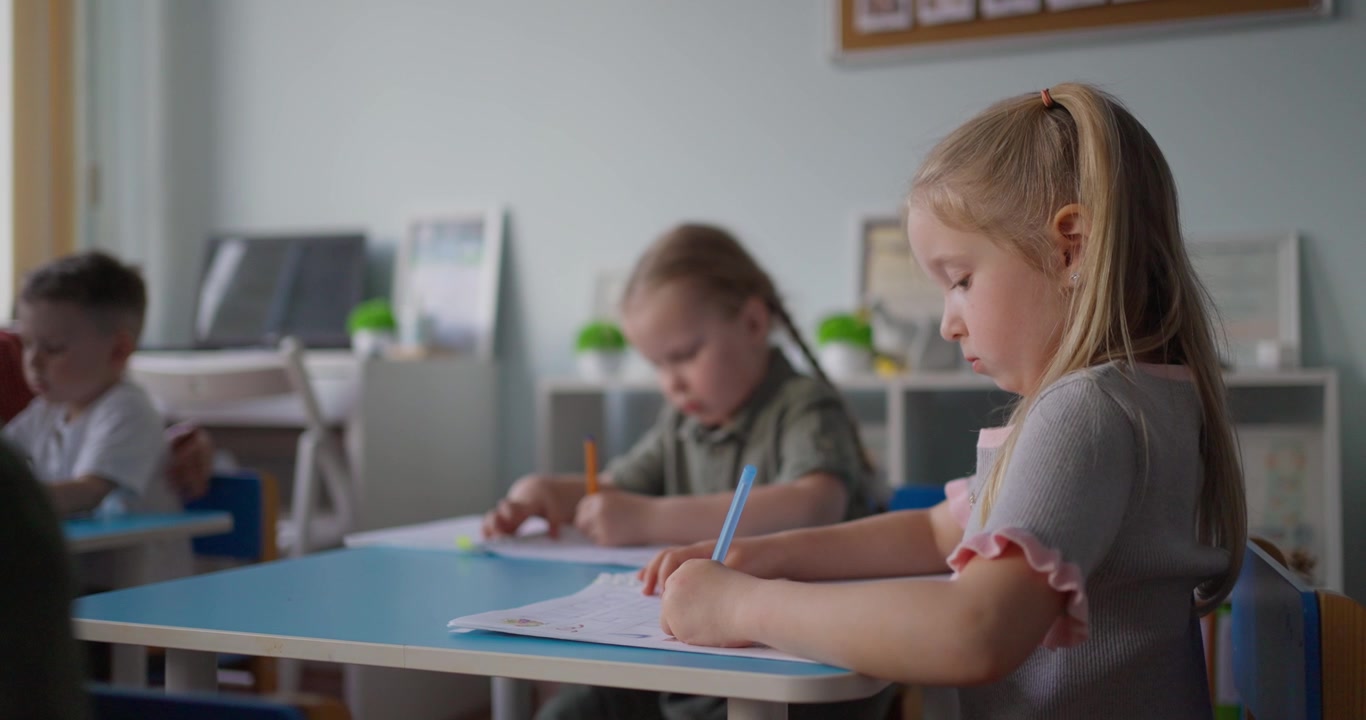 Focused Young Students Writing and Drawing in a Classroom