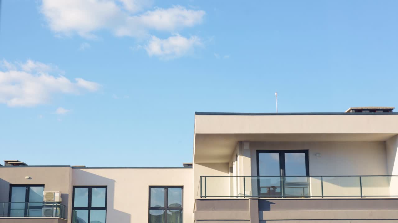 Timelaps of clouds passing over a modern apartment building, reflecting in it's windows