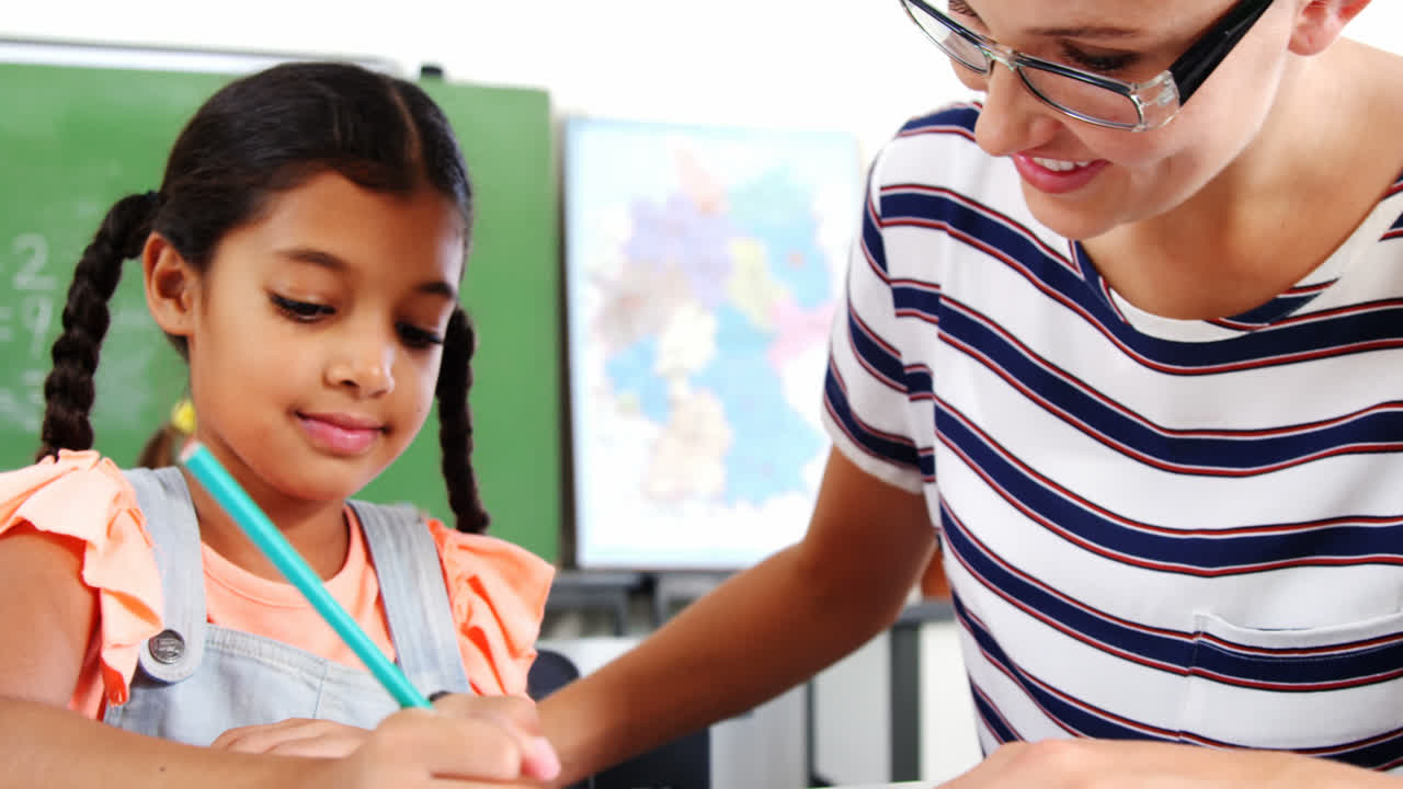 maestra ayudando a una estudiante con su tarea en el aula
