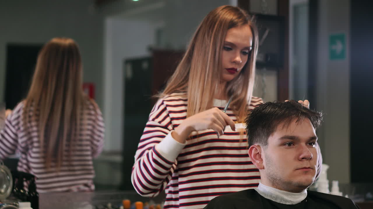 Una parrucchiera che taglia i capelli a un cliente uomo sorridente in un salone di bellezza.