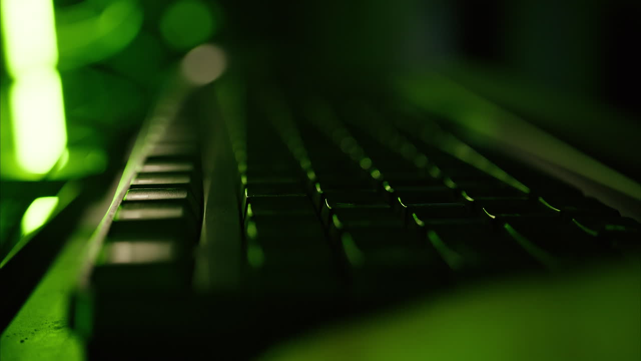 Close up of a man punching the keypad on a computer in a server room with green lights