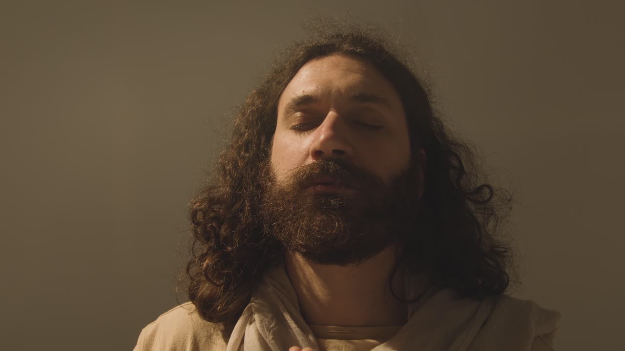 retrato de estudio de un hombre vestido con túnicas con cabello largo y barba que representa la figura de jesucristo orando 4