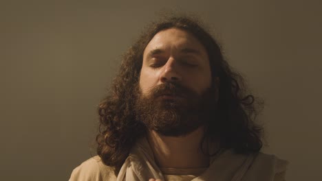 retrato de estudio de un hombre vestido con túnicas con cabello largo y barba que representa la figura de jesucristo orando 4