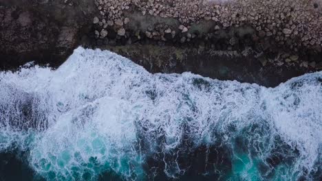 ondas aéreas de arriba hacia abajo que se estrellan sobre una costa rocosa con hermosa espuma de mar blanca y azules vibrantes en oahu hawaii honolulu, muñeca aérea de arriba hacia abajo