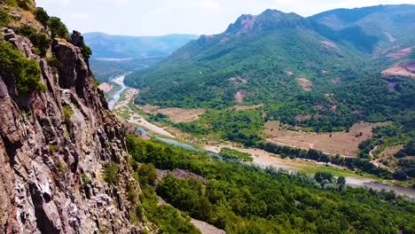 volando por una montaña rocosa con vistas a un río cañón y montañas lejanas