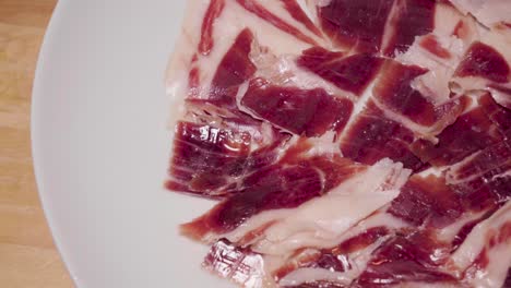 Spanish-Jamon-Iberico-on-White-Plate,-Closeup-Pan-Left-to-Copy-Space