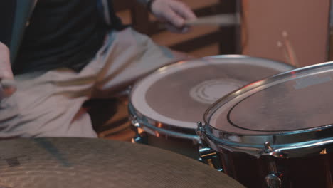 unrecognizable male musician playing drums during a band rehearsal in recording studio